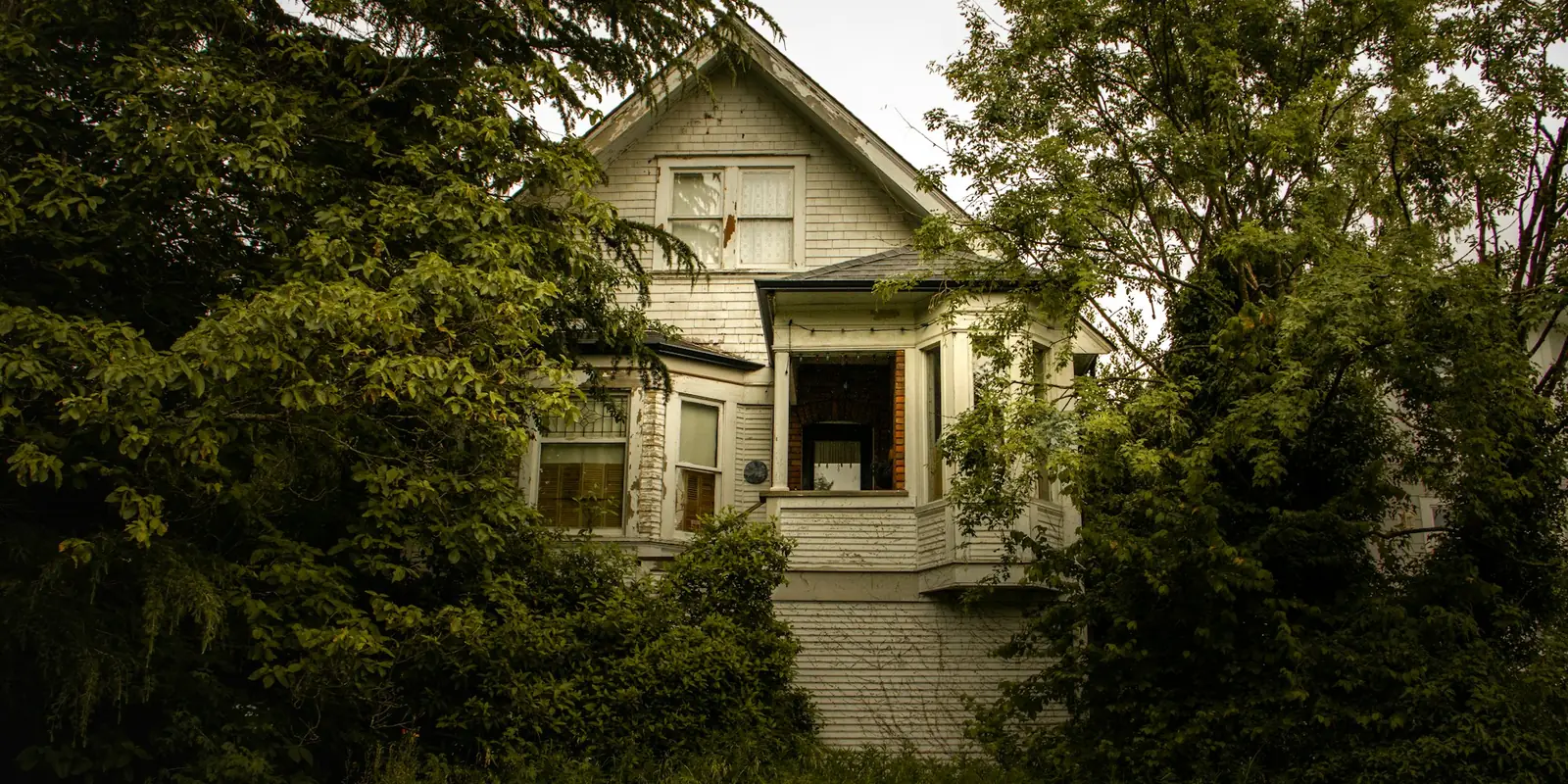 An old wooden house behind trees in Victoria