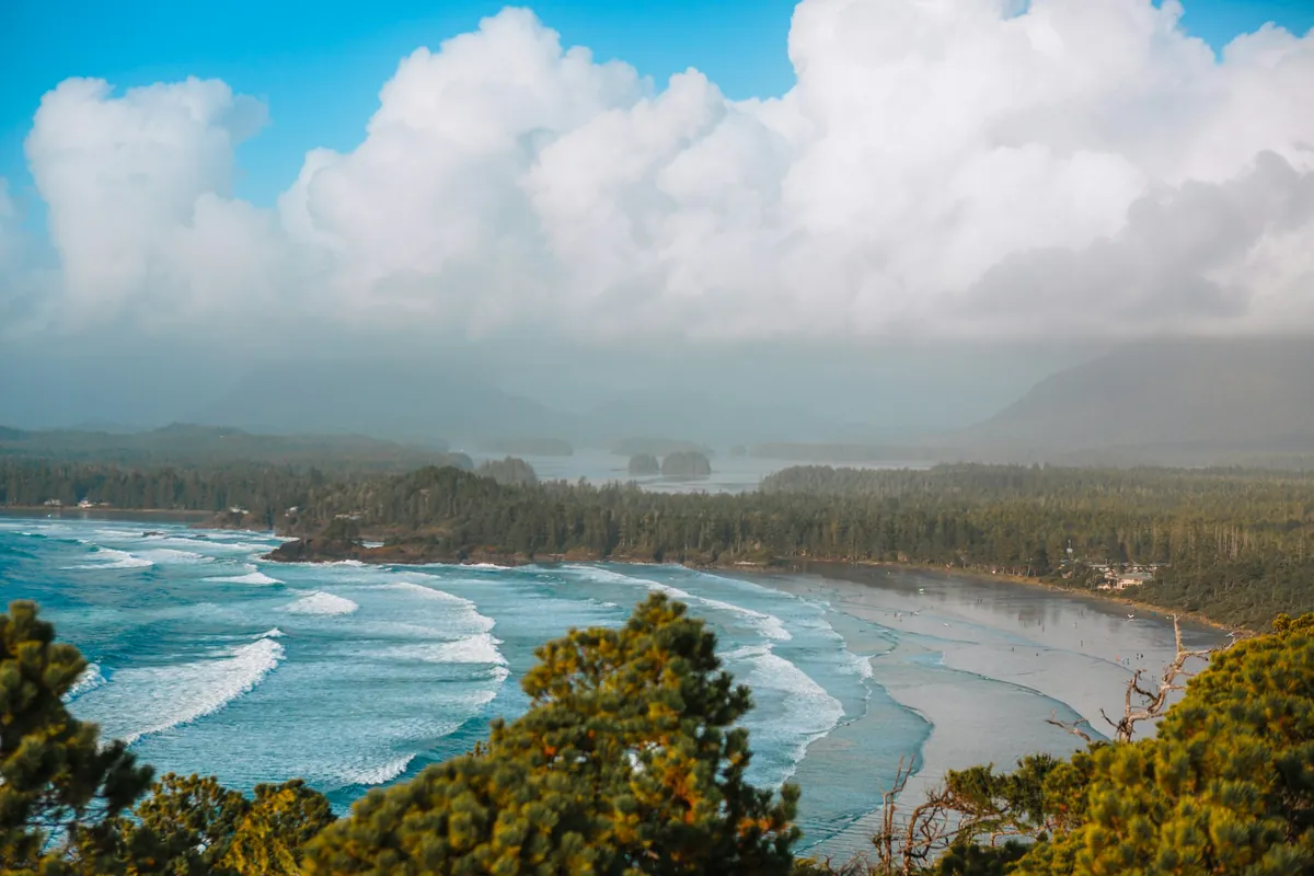 Waves on the beach at Cox Bay in Tofino, seen from a forested hill
